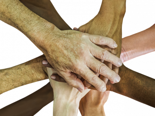 stacked hands of numerous ages and skin colors